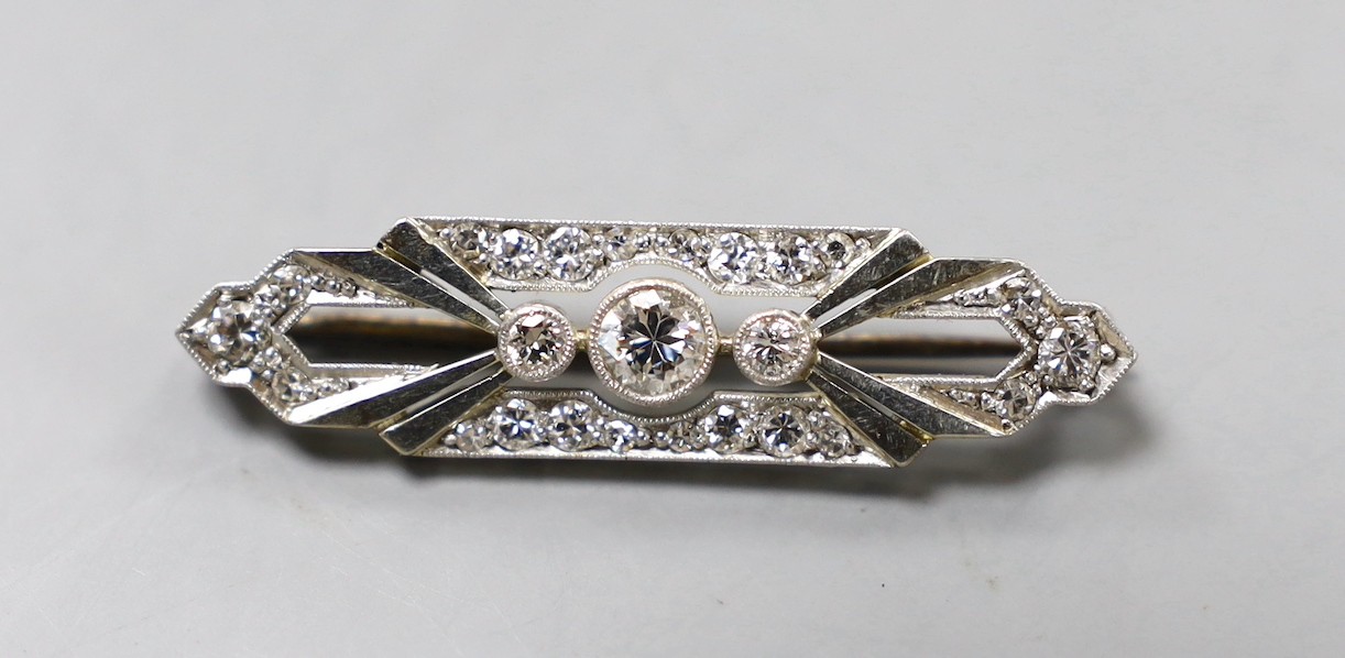 An Art Deco 18ct, plat and diamond cluster shaped bar brooch, with millegrain set stones, 37mm, gross weight 4.7 grams.